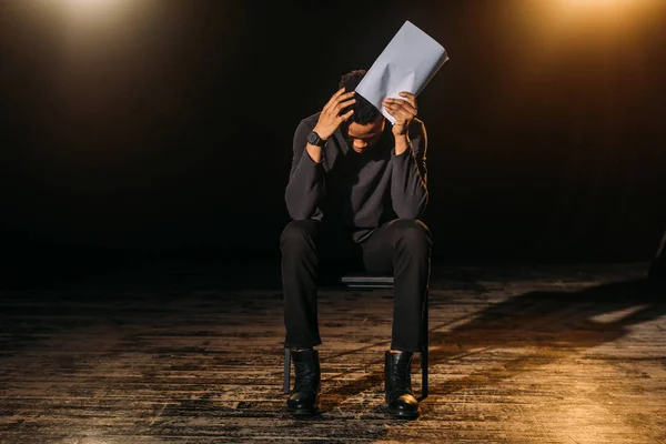 Stressed african american actor holding scenario on stage during rehearse — Stock Photo