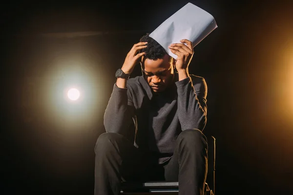Stressed african american actor holding scenario on stage during rehearse — Stock Photo