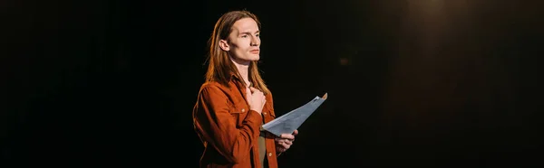 Panoramic shot of handsome actor with screenplay playing on black — Stock Photo