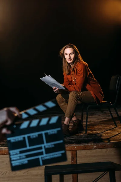 Selective focus of young actor on stage with clapperboard in front — Stock Photo