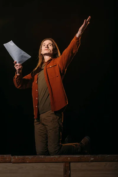 Guapo actor con guion jugando en el escenario durante el ensayo - foto de stock