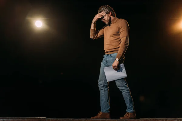 Stressed mature actor holding scenario and standing on stage during rehearse — Stock Photo