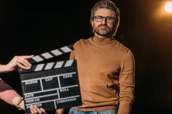 Selective focus of mature actor with clapboard in front — Stock Photo