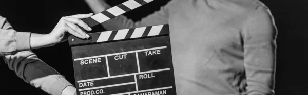 Plan panoramique de l'acteur avec panneau à clins devant, isolé sur noir, noir et blanc — Photo de stock