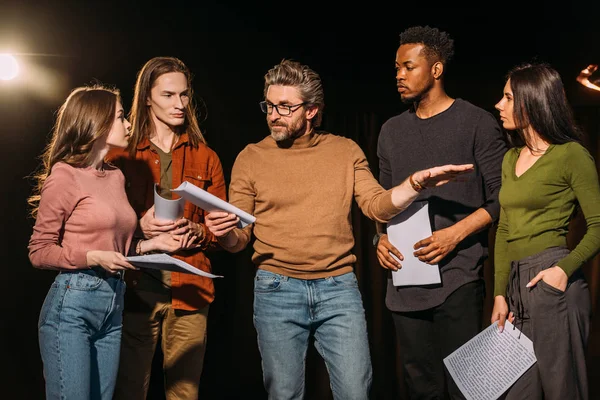 Acteurs et actrices multiethniques répétant avec le metteur en scène du théâtre sur scène — Photo de stock