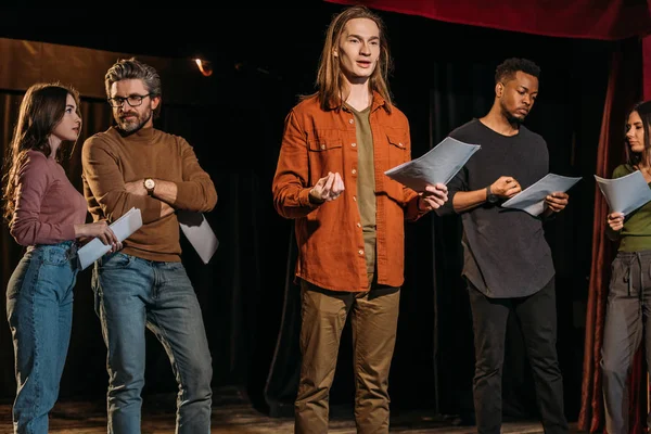 Multikulturelle Schauspieler und Schauspielerinnen proben mit Drehbüchern auf der Bühne im Theater — Stockfoto