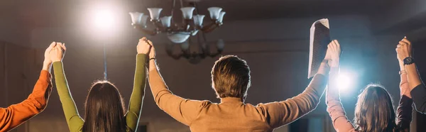 Panoramic shot of actors and actresses with hands up and dramatic lighting — Stock Photo