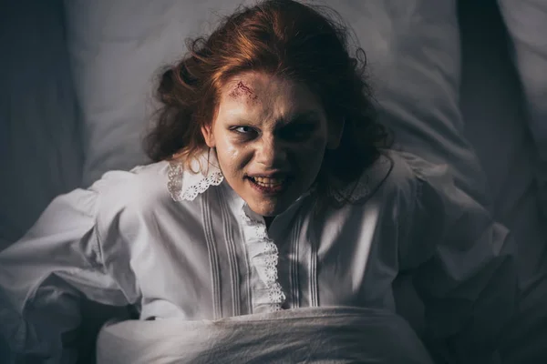 Вид сверху паранормальной девочки в ночном халате, лежащей в постели — стоковое фото