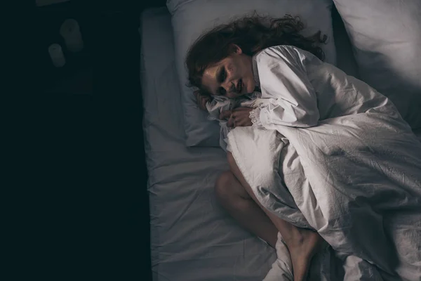 Vue de dessus de démoniaque obsédé femme en chemise de nuit couché dans le lit — Photo de stock