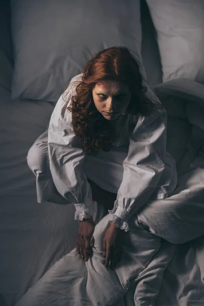 Overhead view of demoniacal scary woman in nightgown sitting in bed — Stock Photo