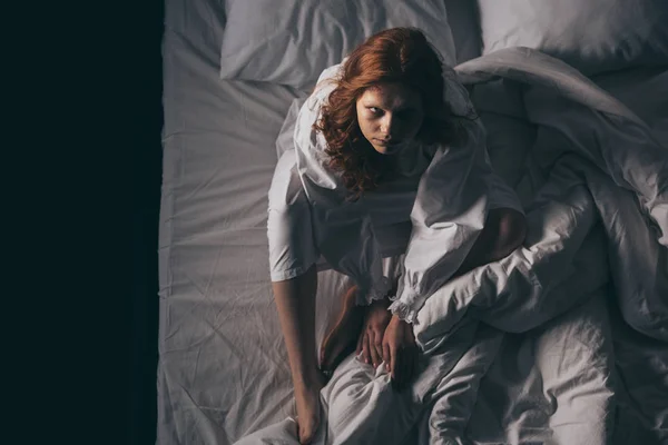 Blick von oben auf dämonische paranormale Frau im Nachthemd, die im Bett sitzt — Stockfoto