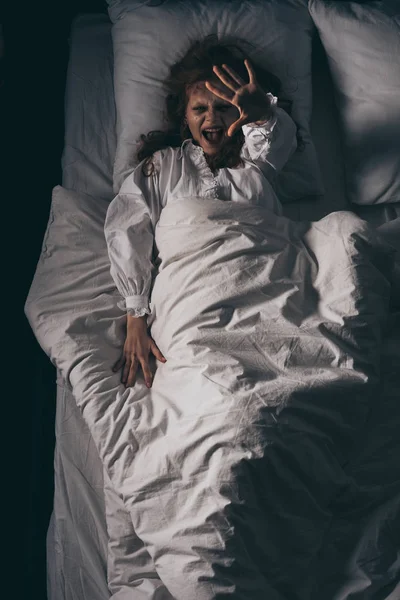 Top view of obsessed girl in nightgown screaming and gesturing in bed — Stock Photo