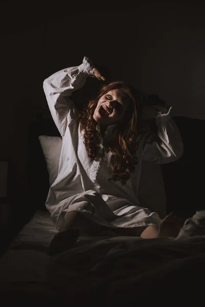 Паранормальна моторошна дівчина в нічній сукні кричить в ліжку — стокове фото