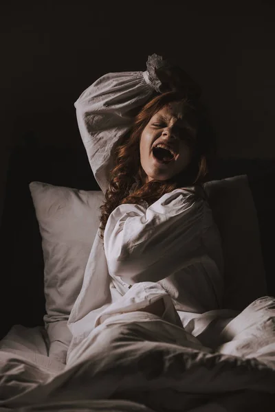 Paranormal gothic girl in nightgown yelling in bed — Stock Photo