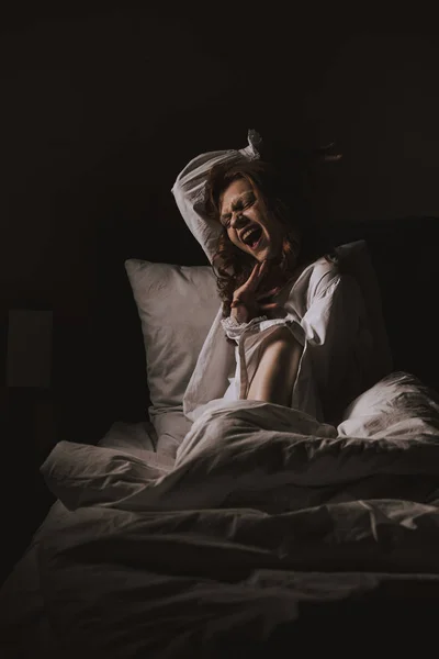 Паранормальная готическая женщина в ночной рубашке кричит в постели — стоковое фото