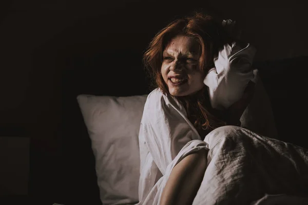 Женщина улыбается дьявол в ночной рубашке, сидя в постели — стоковое фото