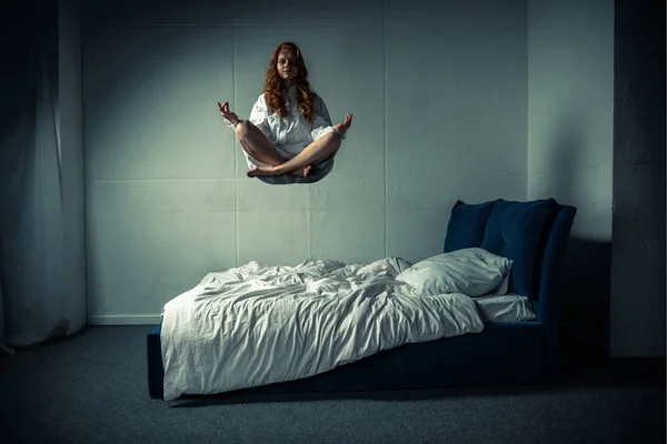 Obsessed girl levitating in lotus pose during meditation over bed — Stock Photo