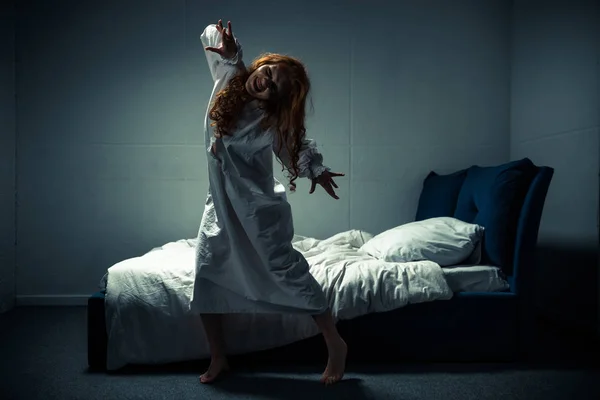 Sonriente mujer obsesionada en camisón de pie cerca de la cama - foto de stock