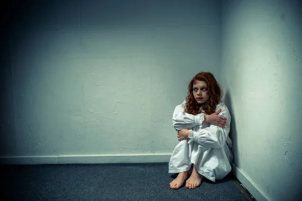 Демоническая злая девушка в ночной рубашке, стоящая у стены — стоковое фото