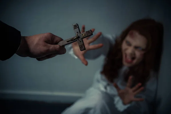 Вибірковий фокус екзорциста тримає хрест перед криком одержимої дівчини — стокове фото