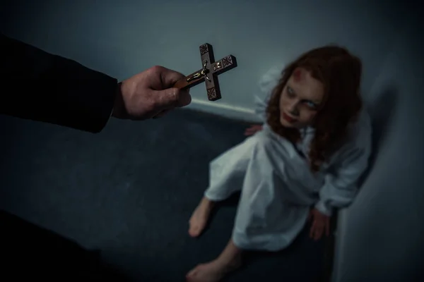 Exorcist holding cross in front of obsessed girl — Stock Photo