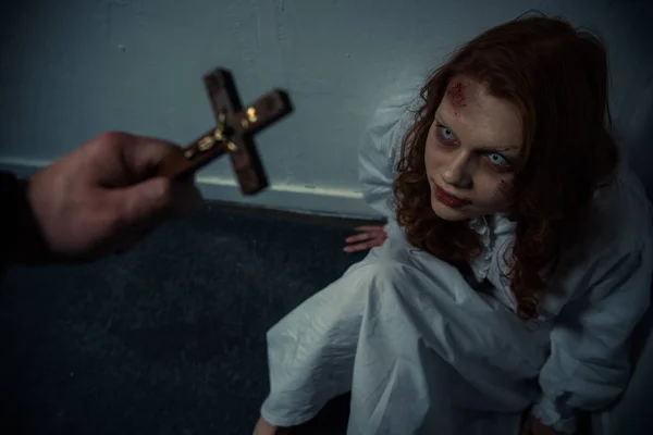 Exorcista sosteniendo cruz delante de chica obsesionada - foto de stock