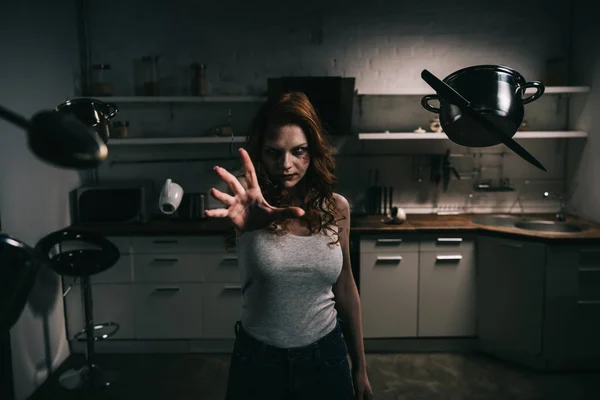 Menina demoníaca concentrado com utensílios de cozinha levitação na cozinha — Fotografia de Stock