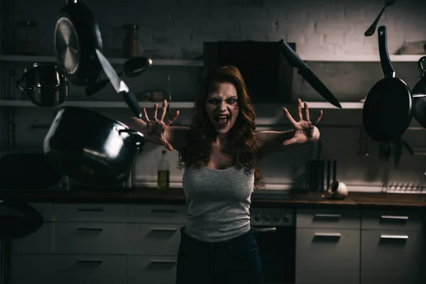 Assustador demoníaco gritando menina com levitação utensílios de cozinha na cozinha — Fotografia de Stock