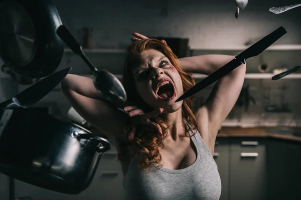 Demoniaca gritando chica con levitación utensilios de cocina en la cocina - foto de stock