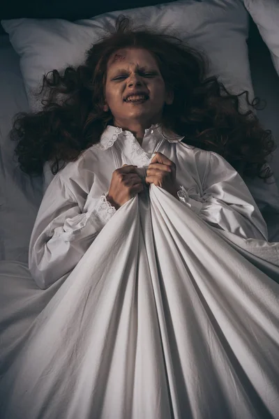 Vista dall'alto della donna demoniaca in camicia da notte sdraiata a letto — Foto stock