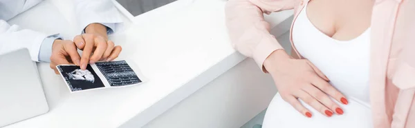 Tiro panorâmico de médico profissional mostrando varredura de ultra-som para mulher grávida jovem — Fotografia de Stock