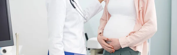 Tiro panorâmico da mulher grávida que tem consulta com o médico na clínica ginecológica — Fotografia de Stock