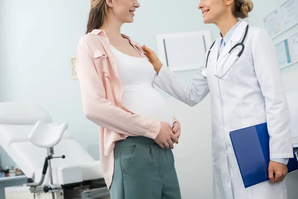 Vista recortada de la mujer embarazada feliz teniendo consulta con el médico en la clínica ginecológica - foto de stock