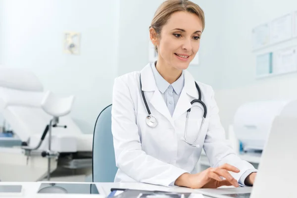 Profesional hermoso médico que trabaja en el ordenador portátil en la clínica - foto de stock