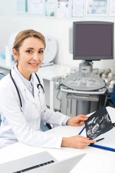 Sonriente médico rubio mostrando ultrasonido exploración en clínica - foto de stock