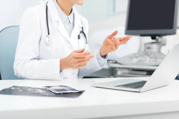 Professional female doctor working on laptop in clinic with ultrasound scanner — Stock Photo