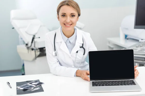 Professionnel souriant médecin féminin avec échographie montrant ordinateur portable avec écran blanc — Photo de stock