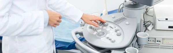 Cropped view of female doctor working with ultrasound scanner in clinic, panoramic shot — Stock Photo