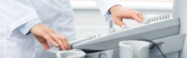 Частковий вид на професійного лікаря, який працює з ультразвуковим сканером у клініці, панорамний знімок — стокове фото