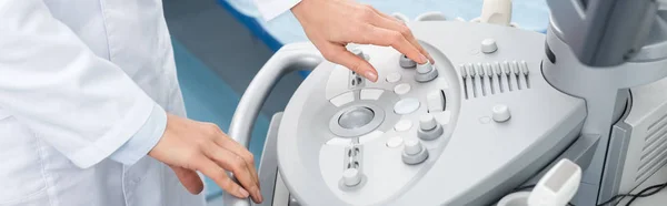 Панорамный снимок профессионального врача, работающего с ультразвуковым сканером в клинике — стоковое фото