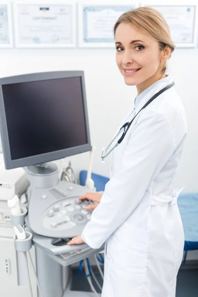 Médico profesional que trabaja con escáner de ultrasonido con pantalla en blanco en la clínica - foto de stock
