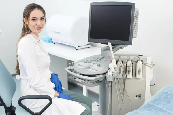 Junger glücklicher Arzt arbeitet mit Ultraschallscanner mit leerem Bildschirm in Klinik — Stockfoto