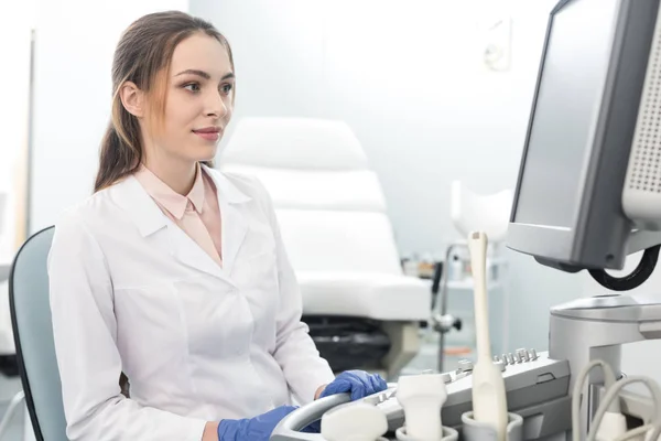 Doctora joven que trabaja con escáner de ultrasonido en la clínica - foto de stock