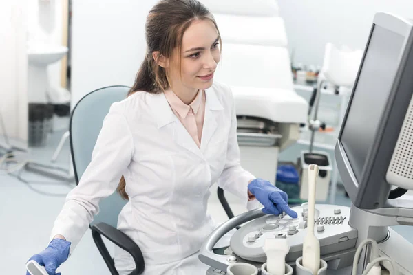 Young smiling doctor working with ultrasound scanner in clinic — Stock Photo