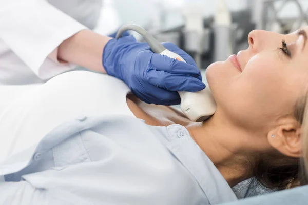 Doctor examining thyroid of woman with ultrasound scan in clinic — Stock Photo