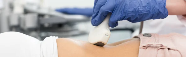 Panoramic shot of doctor examining stomach of patient with ultrasound scan in clinic — Stock Photo