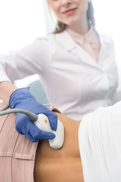 Visão cortada de jovem médico examinando rim de paciente feminino com ultra-som na clínica — Fotografia de Stock