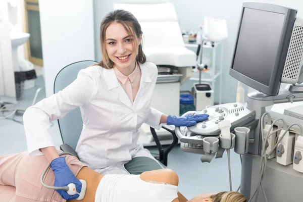 Sorridente jovem médico examinando rim de paciente feminino com ultra-som na clínica — Fotografia de Stock