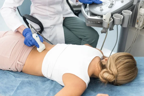 Vista recortada del médico examinando el riñón de la paciente femenina con ecografía en la clínica - foto de stock