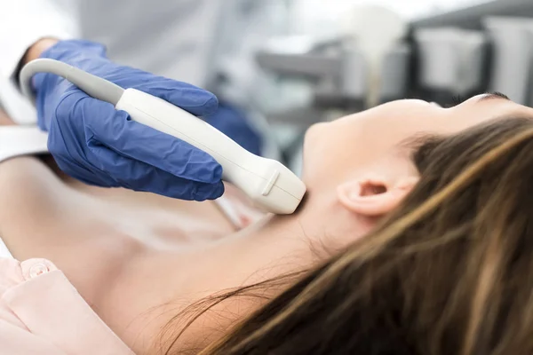 Doctor examining thyroid of female patient with ultrasound scan in clinic — Stock Photo